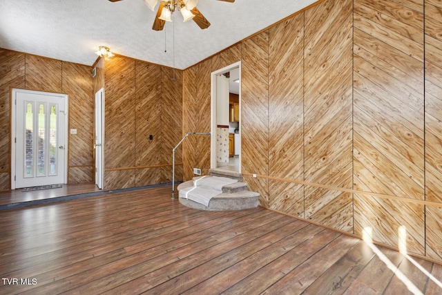 interior space with a textured ceiling, wooden walls, and hardwood / wood-style floors