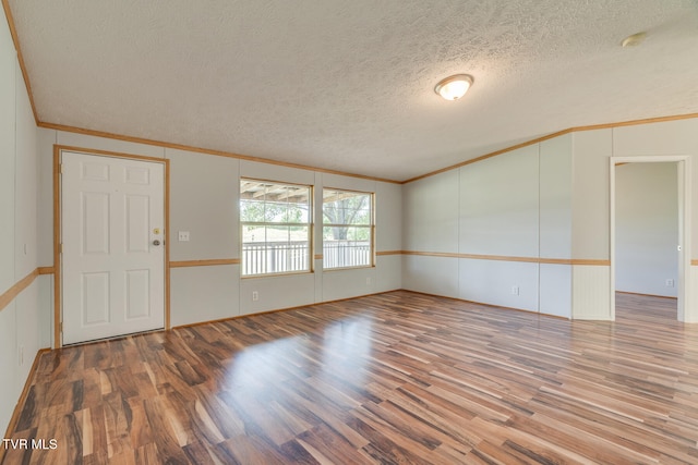 spare room featuring wood-type flooring, a textured ceiling, and ornamental molding