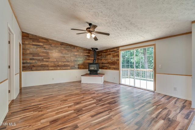 unfurnished living room featuring a wood stove, hardwood / wood-style floors, and a textured ceiling