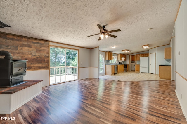 unfurnished living room featuring a textured ceiling, light hardwood / wood-style floors, and a wood stove