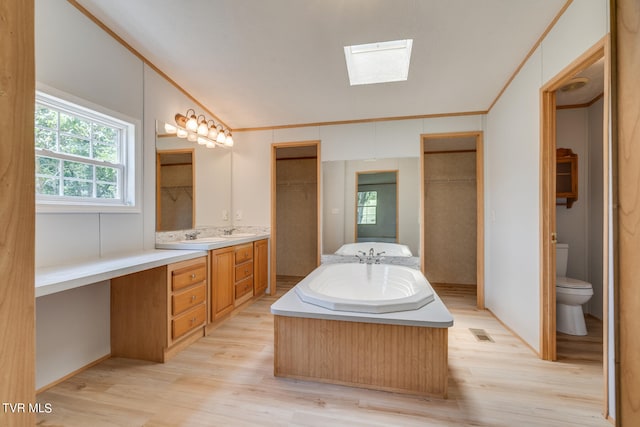 bathroom featuring a tub to relax in, toilet, vanity, and hardwood / wood-style flooring