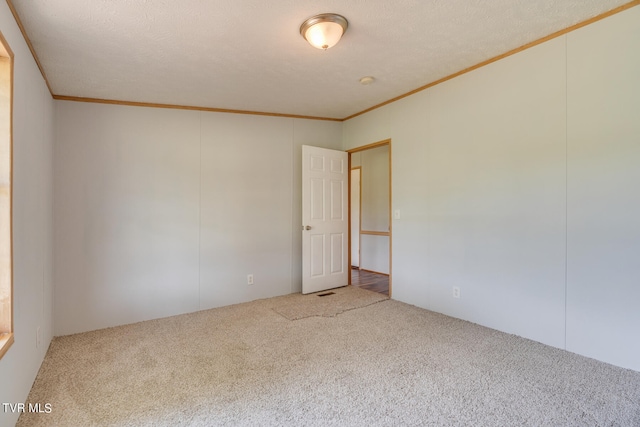 unfurnished room with carpet floors, a textured ceiling, and ornamental molding