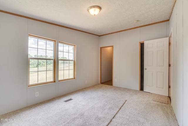 unfurnished bedroom with a textured ceiling, carpet floors, and crown molding