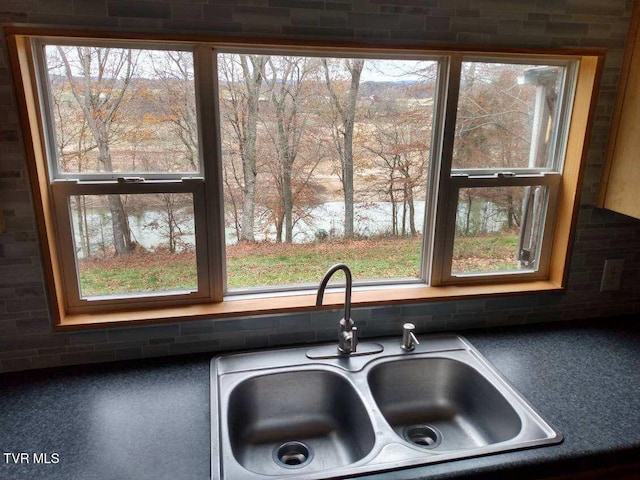 interior details with backsplash, a water view, and sink