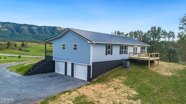 view of property exterior featuring a mountain view, central AC, a lawn, and a garage