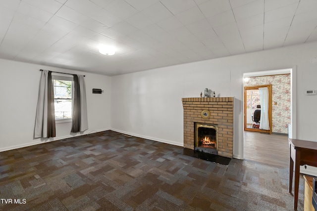 unfurnished living room with dark colored carpet and a fireplace