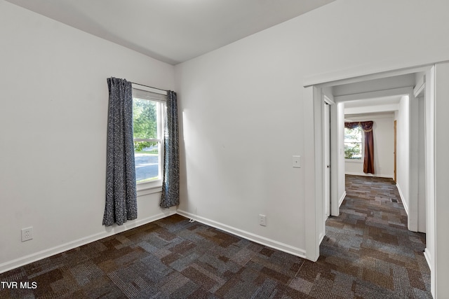 empty room with a healthy amount of sunlight and dark carpet