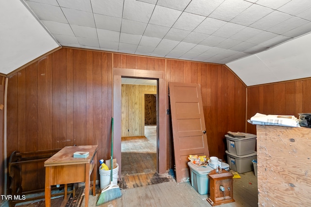 additional living space with wood walls, hardwood / wood-style flooring, and vaulted ceiling