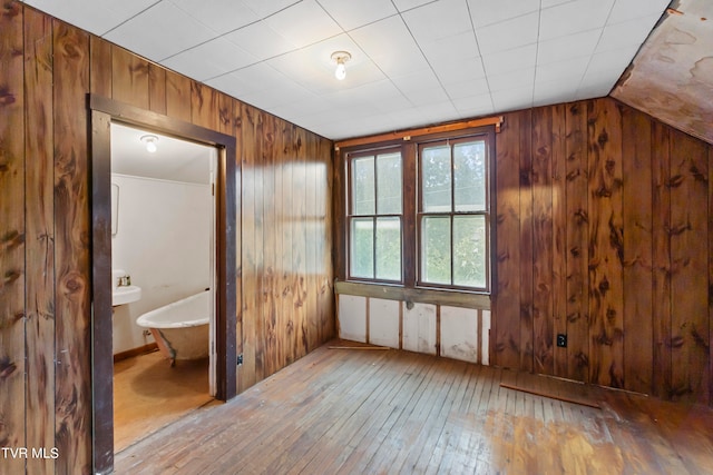 interior space with wood walls, lofted ceiling, wood-type flooring, and connected bathroom