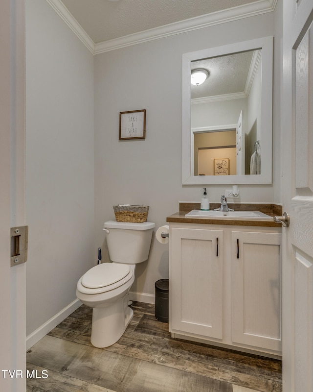 bathroom with toilet, crown molding, vanity, and wood-type flooring