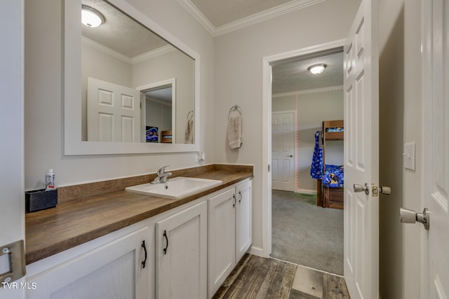 bathroom featuring vanity, crown molding, hardwood / wood-style floors, and a textured ceiling