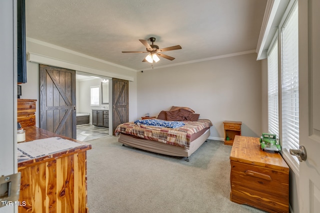 bedroom featuring carpet, ceiling fan, a barn door, ornamental molding, and ensuite bathroom