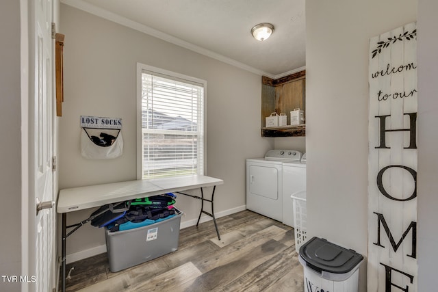 clothes washing area featuring crown molding, wood-type flooring, separate washer and dryer, and cabinets