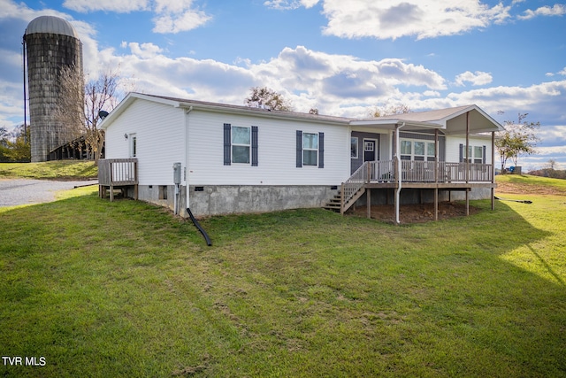 back of property with a wooden deck and a lawn