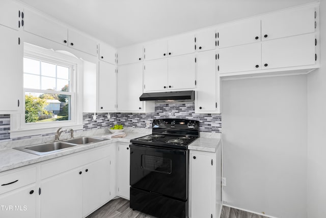 kitchen with black / electric stove, decorative backsplash, sink, and white cabinetry