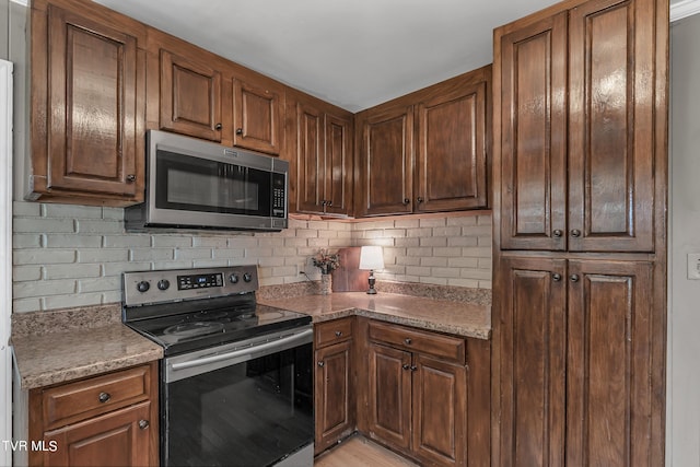 kitchen featuring light hardwood / wood-style floors, tasteful backsplash, and appliances with stainless steel finishes