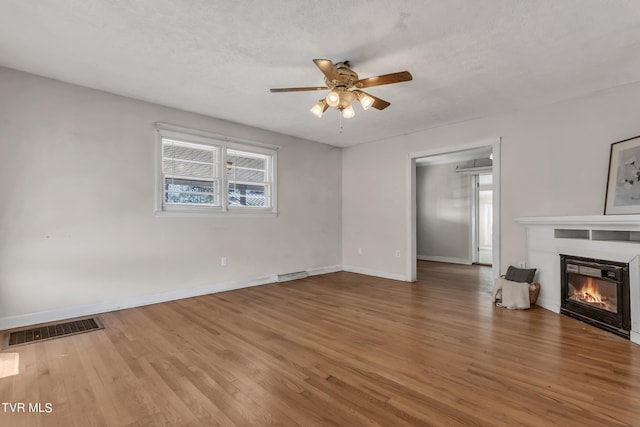 unfurnished living room with a textured ceiling, wood-type flooring, and ceiling fan