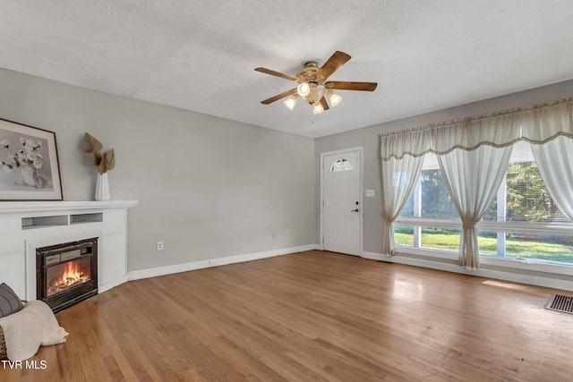 unfurnished living room featuring ceiling fan, a textured ceiling, and hardwood / wood-style floors