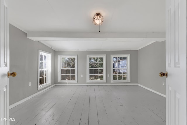 spare room with beam ceiling, a healthy amount of sunlight, and light wood-type flooring