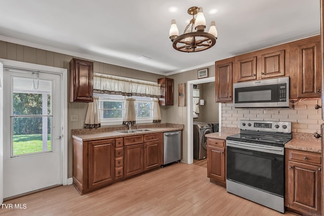 kitchen featuring appliances with stainless steel finishes, separate washer and dryer, light wood-type flooring, crown molding, and sink