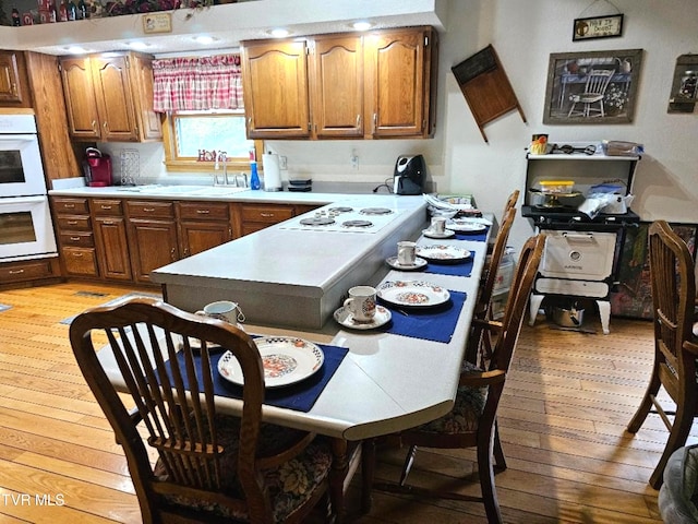 kitchen with white appliances, light hardwood / wood-style flooring, and sink