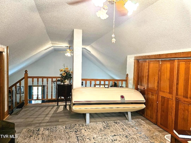 bedroom featuring lofted ceiling, wood-type flooring, and a textured ceiling