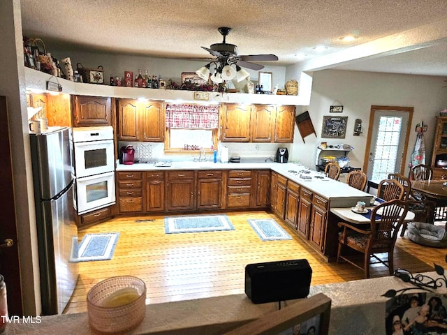 kitchen featuring light hardwood / wood-style flooring, a textured ceiling, white appliances, and ceiling fan