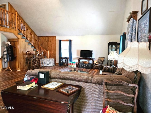 living room featuring hardwood / wood-style flooring, vaulted ceiling, and wooden walls