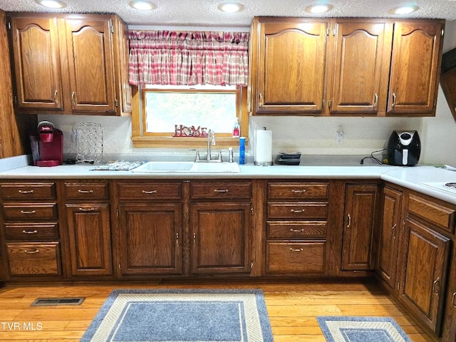 kitchen with a textured ceiling, sink, and light wood-type flooring