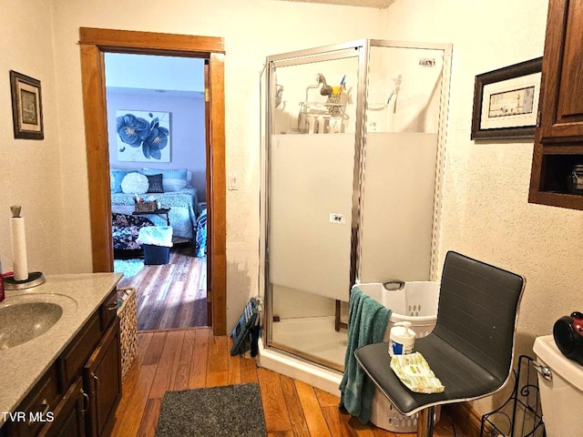 bathroom with vanity, toilet, a shower with shower door, and wood-type flooring