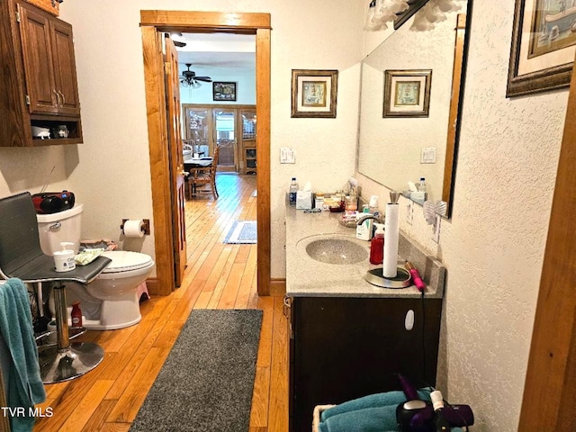 bathroom featuring toilet, hardwood / wood-style floors, vanity, and ceiling fan