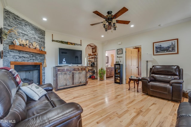 living room featuring light hardwood / wood-style floors, ornamental molding, a fireplace, and ceiling fan