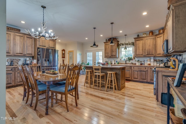 dining space with an inviting chandelier, crown molding, light wood-type flooring, and french doors