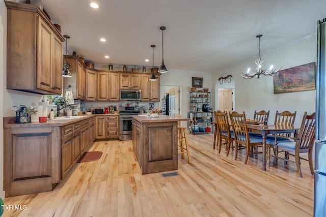 kitchen with hanging light fixtures, light hardwood / wood-style flooring, ornamental molding, stainless steel appliances, and a center island