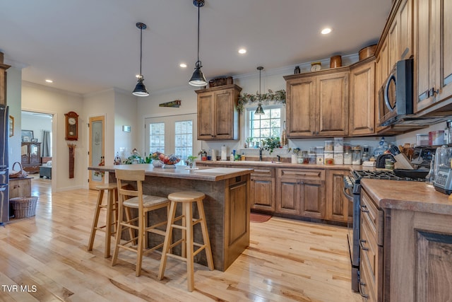 kitchen featuring appliances with stainless steel finishes, light hardwood / wood-style flooring, a kitchen island, and ornamental molding