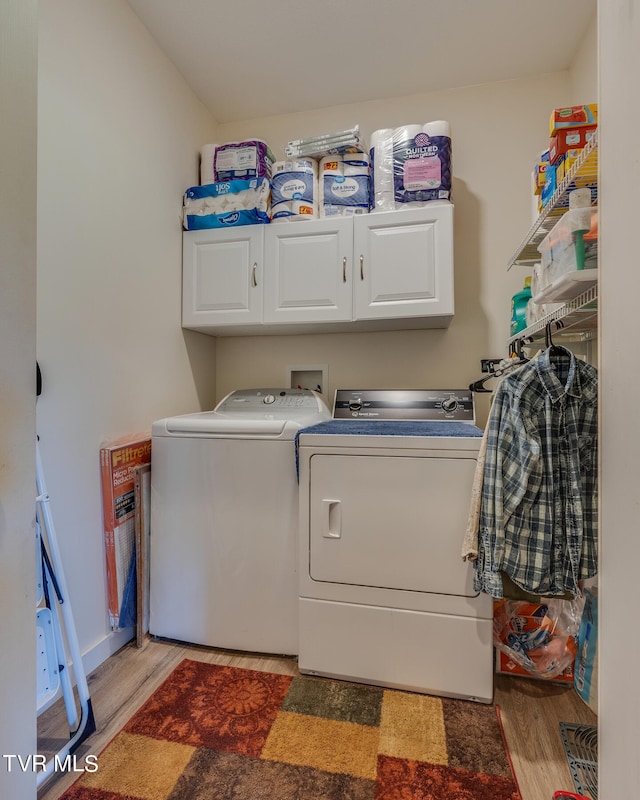 laundry room with cabinets, separate washer and dryer, and light wood-type flooring