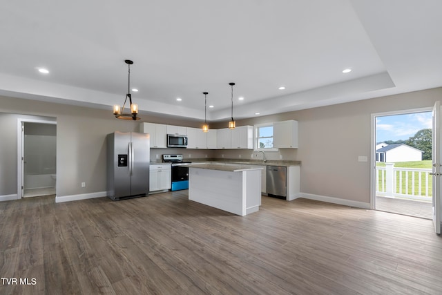 kitchen with light wood-type flooring, stainless steel appliances, pendant lighting, white cabinets, and a center island