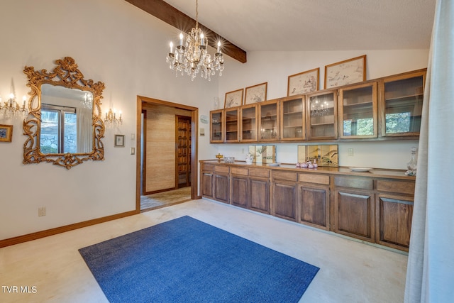 interior space featuring a textured ceiling, vaulted ceiling with beams, pendant lighting, dark brown cabinetry, and light colored carpet