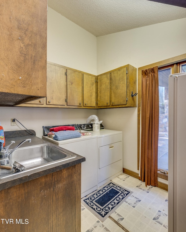 washroom with cabinets, a textured ceiling, sink, and washing machine and dryer