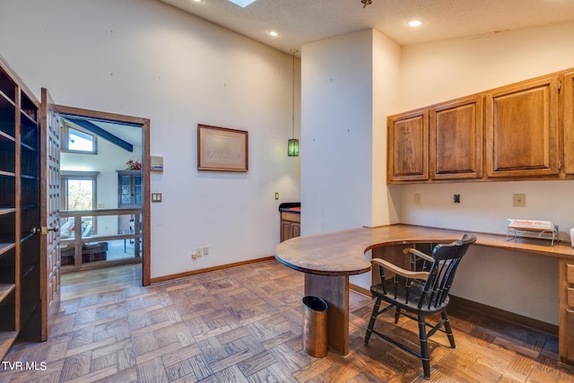 office space with built in desk, parquet flooring, and a textured ceiling