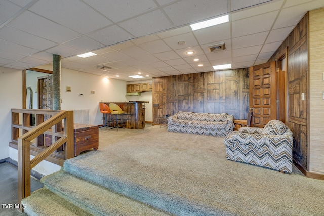 living room featuring a drop ceiling, carpet floors, and wooden walls