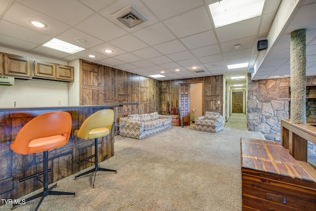 living room featuring a paneled ceiling, bar, and dark carpet