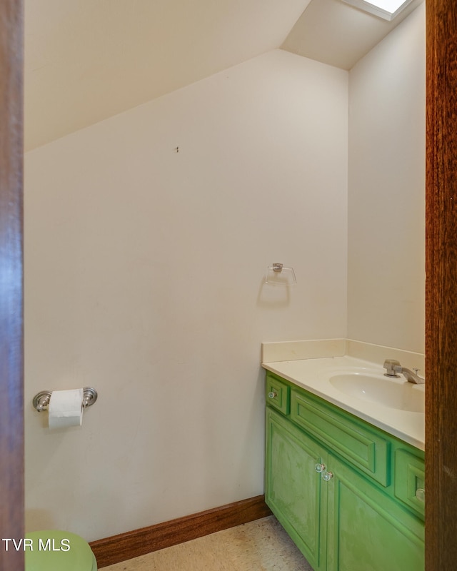 bathroom with vanity, toilet, and vaulted ceiling with skylight