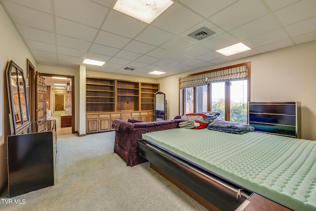 carpeted bedroom featuring a drop ceiling and connected bathroom