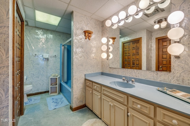 full bathroom with toilet, a drop ceiling, vanity, and tub / shower combination