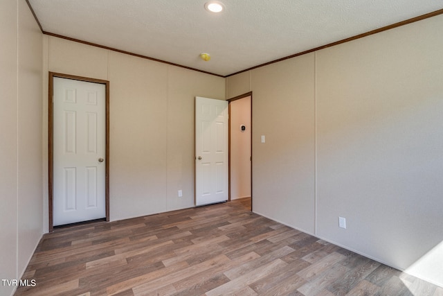 unfurnished bedroom featuring crown molding, a textured ceiling, and wood-type flooring