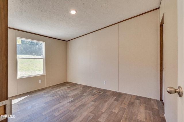 unfurnished room with crown molding, hardwood / wood-style flooring, and a textured ceiling