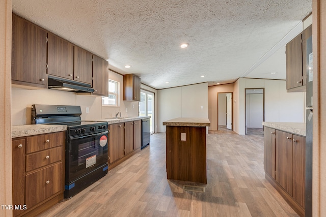 kitchen featuring black range with gas stovetop, a center island, light hardwood / wood-style flooring, and a textured ceiling