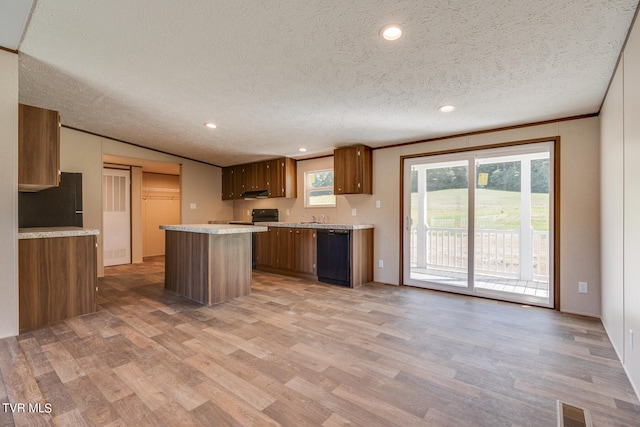 kitchen featuring wood-type flooring, ornamental molding, black appliances, a center island, and a textured ceiling