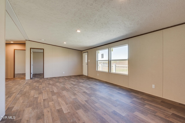 empty room with wood-type flooring and a textured ceiling